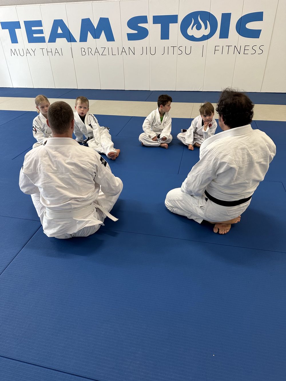Kids sitting in a circle with coaches during kids BJJ at Stoic Martial Arts in Chanhassen, Minnesota